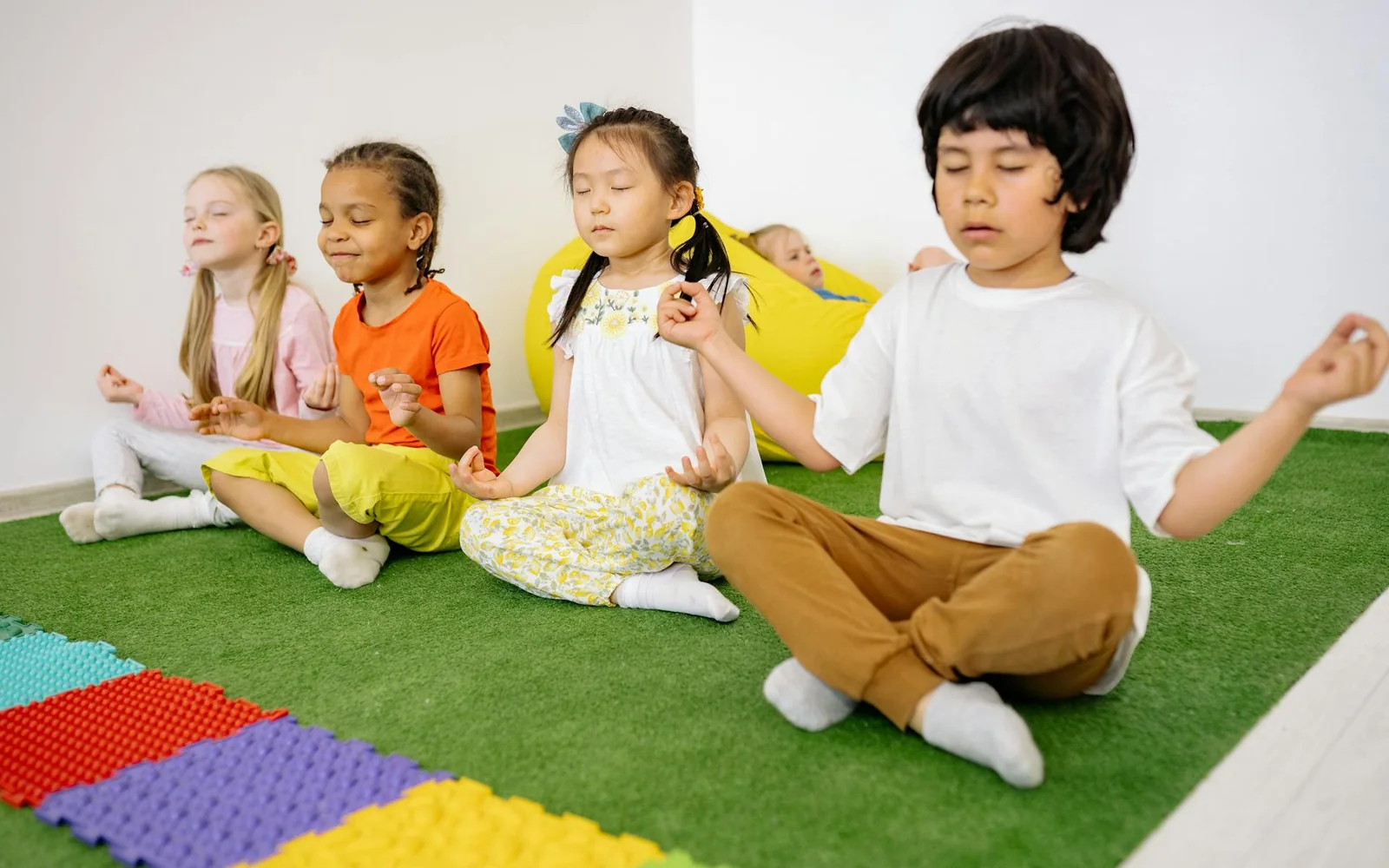 Children sitting cross-legged with eyes closed during a meditation activity.